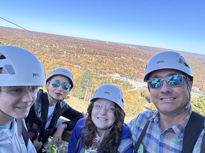 Anfisa and her family in zip line helmets above autumn hills